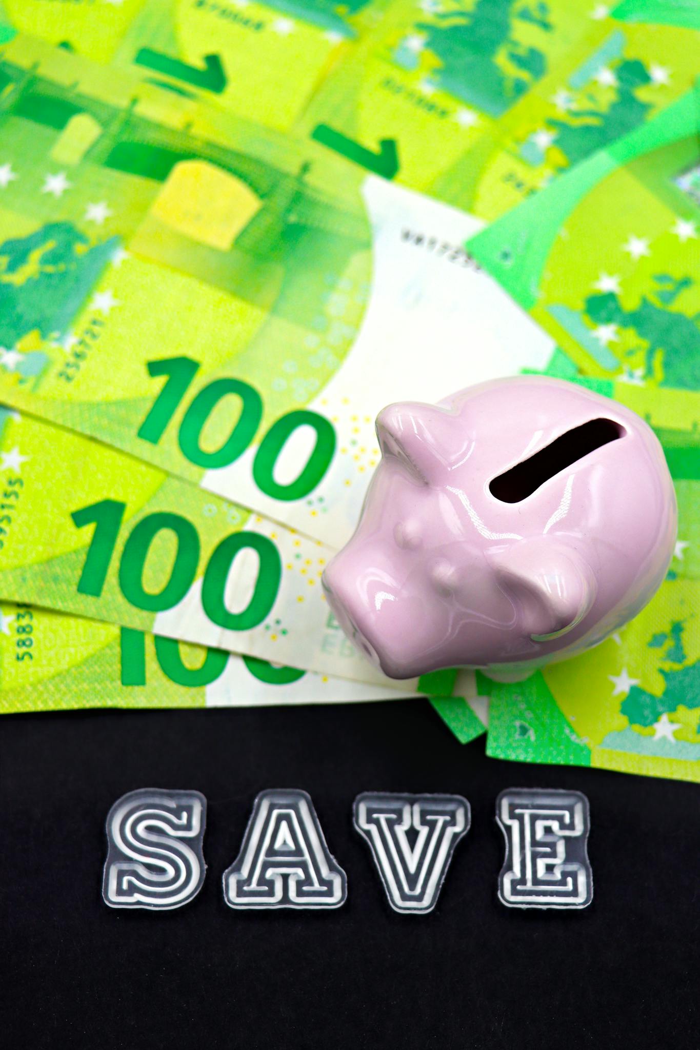 Pink piggy bank on Euro banknotes with 'SAVE' text, symbolizing financial savings.